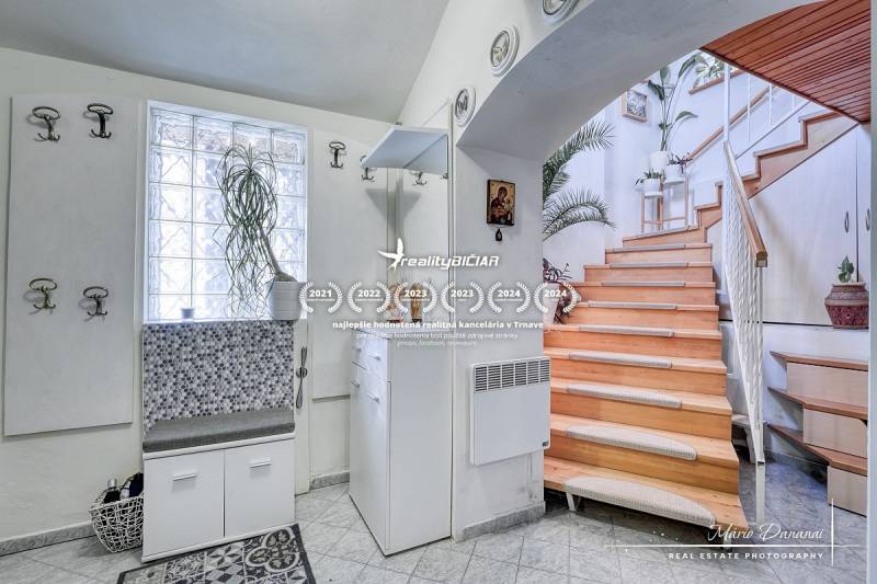 Rekreačná chata s úžasným výhľadom v prestížnej lokalite Devín - Chata s dreveným schodiskom, bielym nábytkom a rastlinou; interiér s podlahou s dreveným dekorom.