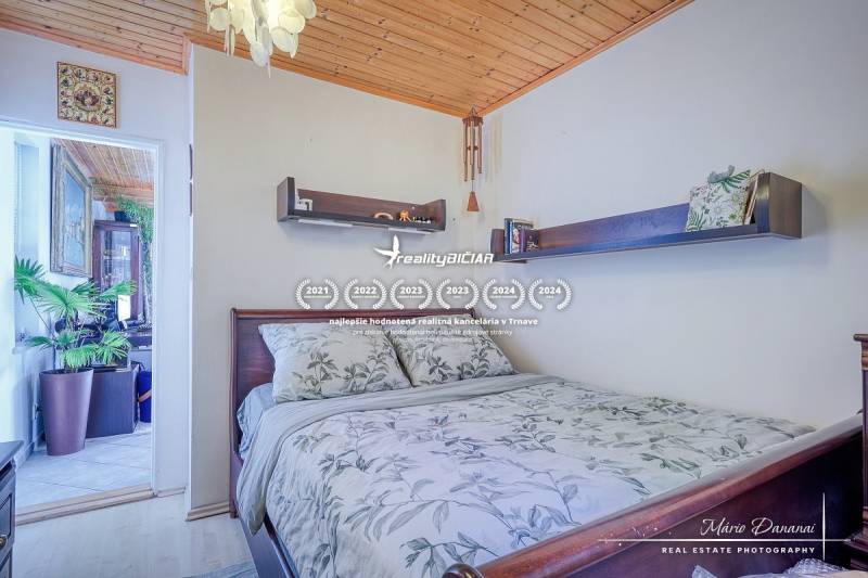 Rekreačná chata s úžasným výhľadom v prestížnej lokalite Devín - Spálňa v Chate s dreveným stropom, kvetinami a poličkami nad posteľou.