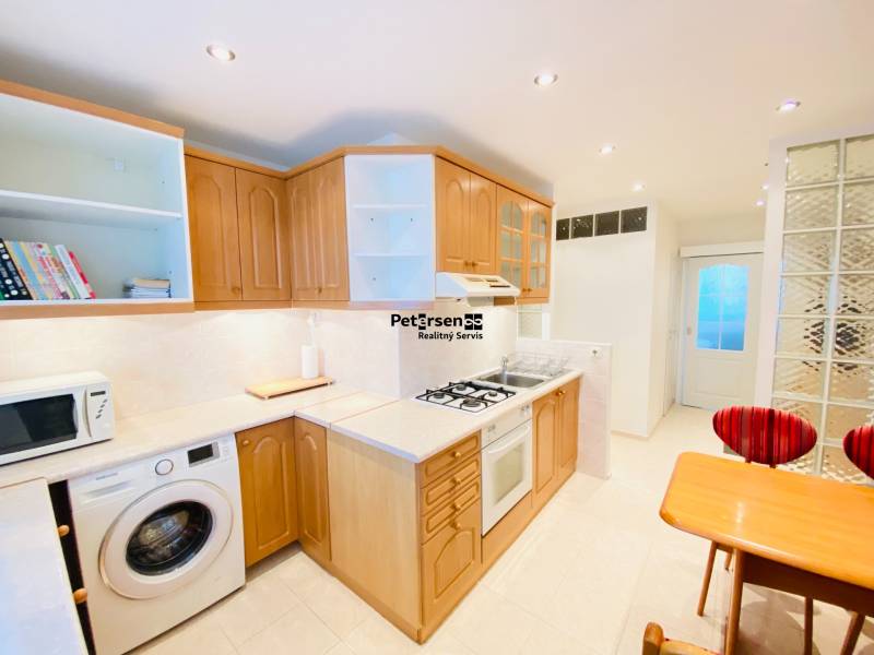 NA PRENÁJOM PRIESTRANNÝ 3-IZBOVÝ BYT V SKVELEJ LOKALITE, UL. SLOBODY - Kuchyňa v 3-izbovom byte s drevenými skrinkami, pultom a sporákom.