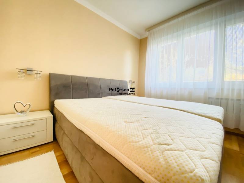 NA PRENÁJOM PRIESTRANNÝ 3-IZBOVÝ BYT V SKVELEJ LOKALITE, UL. SLOBODY - Spálňa s posteľou, nočný stolík, svetlá stena a podlaha s dreveným dekorom.