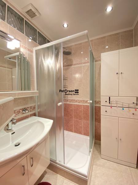 NA PRENÁJOM PRIESTRANNÝ 3-IZBOVÝ BYT V SKVELEJ LOKALITE, UL. SLOBODY - Kúpeľňa v 3-izbovom byte s priehľadným sprchovacím kútom, bielym nábytkom a umývadlom.