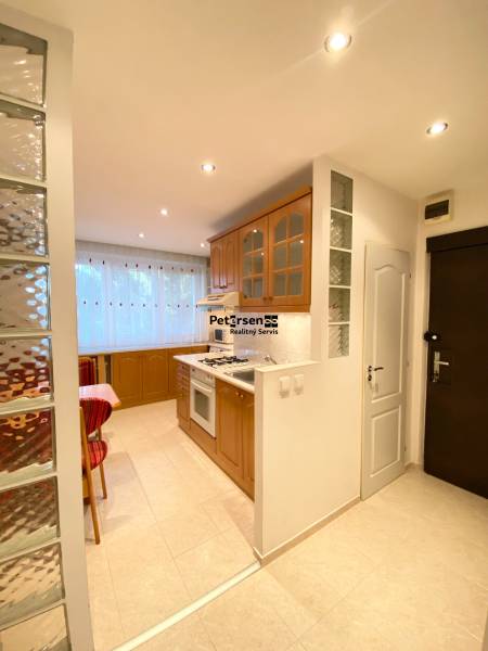 NA PRENÁJOM PRIESTRANNÝ 3-IZBOVÝ BYT V SKVELEJ LOKALITE, UL. SLOBODY - Kuchyňa v 3-izbovom byte s dreveným dekorom a sklenenou tehlovou stenou.