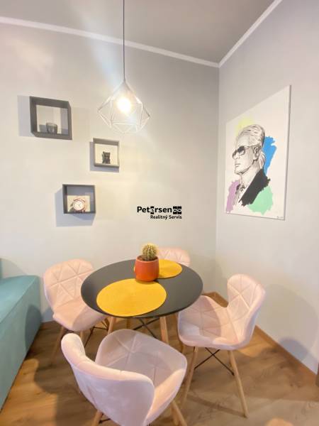 NA PRENÁJOM NADŠTANDARDNÝ 2-IZBOVÝ BYT V CENTRE MESTA - Jedálenský kút v 2-izbovom byte s okrúhlym stolom a dekoráciami na stene.