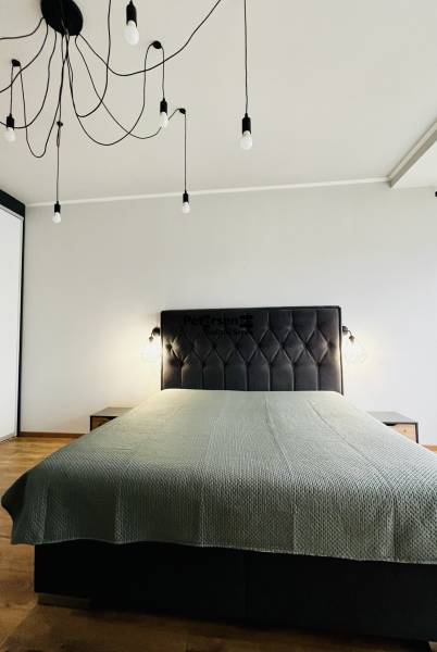 NA PRENÁJOM NADŠTANDARDNÝ 2-IZBOVÝ BYT V CENTRE MESTA - Spálňa v 2-izbovom byte so svetelnými závesmi a posteľou, podlaha s dreveným dekorom.