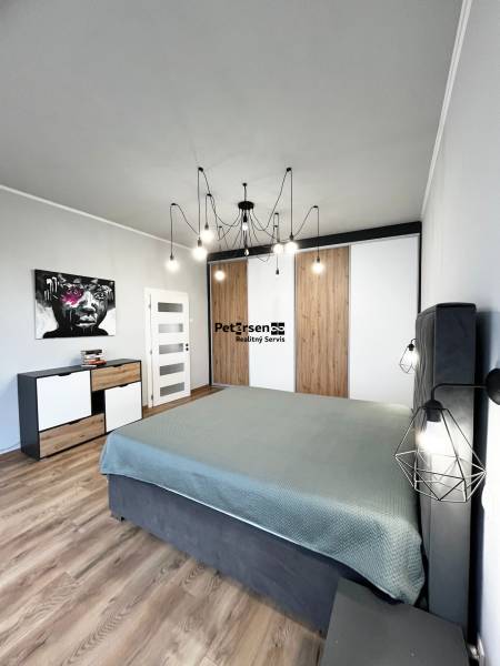 NA PRENÁJOM NADŠTANDARDNÝ 2-IZBOVÝ BYT V CENTRE MESTA - Spálňa v 2-izbovom byte s podlahou s dreveným dekorom, obrazom a minimalistickým lustrom.