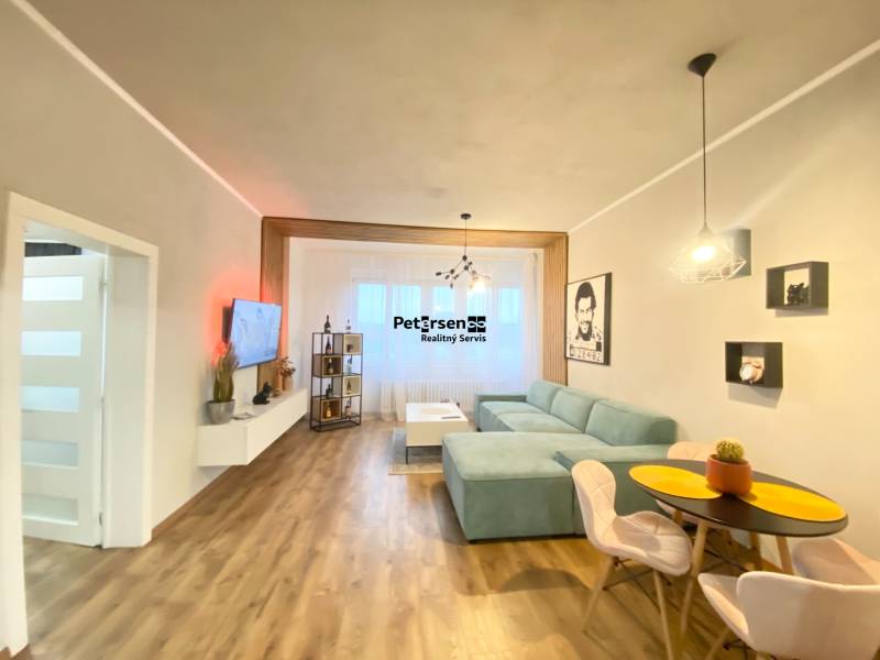 NA PRENÁJOM NADŠTANDARDNÝ 2-IZBOVÝ BYT V CENTRE MESTA - Obývacia izba v 2-izbovom byte s podlahou s dreveným dekorom a pohodlnou sedačkou.