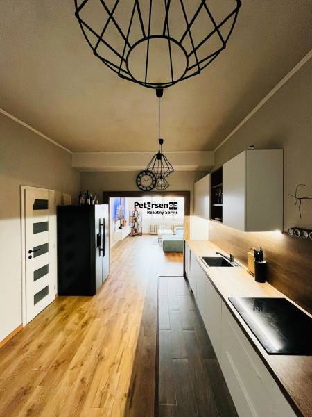 NA PRENÁJOM NADŠTANDARDNÝ 2-IZBOVÝ BYT V CENTRE MESTA - Kuchyňa v 2-izbovom byte s podlahou s dreveným dekorom, viditeľná je aj obývacia časť.