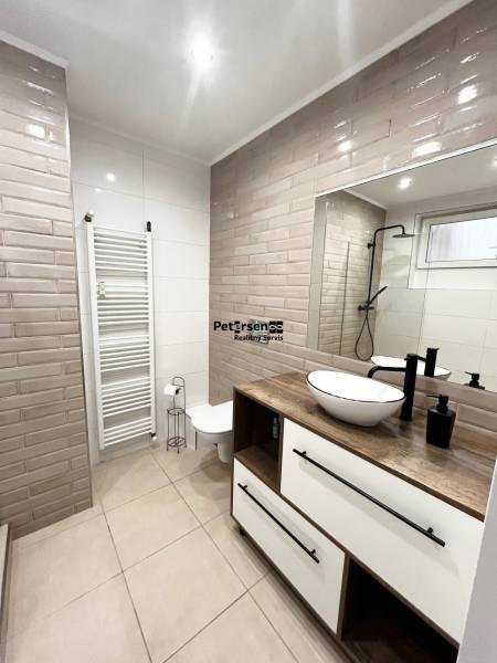 NA PRENÁJOM NADŠTANDARDNÝ 2-IZBOVÝ BYT V CENTRE MESTA - Kúpeľňa obsahuje sprchový kút s čiernym rámom, umývadlo a toaletu.