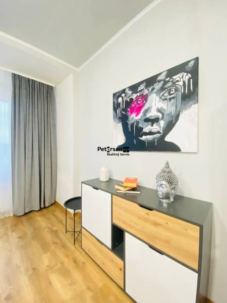 NA PRENÁJOM NADŠTANDARDNÝ 2-IZBOVÝ BYT V CENTRE MESTA - Interiér 2-izbového bytu s komodou, podlahou s dreveným dekorom a výrazným obrazom na stene.