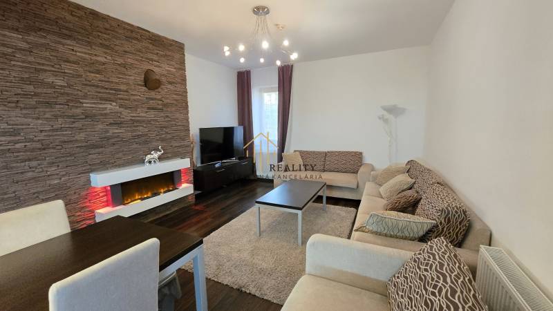 HD REALITY, Vám ponúka na Predaj 3-izbový Apartmán + Garážové státie - Obývačka v 3-izbovom byte s krbom, podlahou s dreveným dekorom a pohodlným sedením.