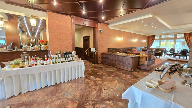 HD REALITY, Vám ponúka na Predaj 3-izbový Apartmán + Garážové státie - Reštaurácia s vínami, stolom s jedlom, drevenou výzdobou a presvetleným sedením.