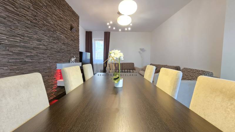 HD REALITY, Vám ponúka na Predaj 3-izbový Apartmán + Garážové státie - Jedálenský stôl v 3-izbovom byte s kamenným obkladom a pohodlnými stoličkami.