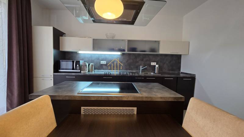 HD REALITY, Vám ponúka na Predaj 3-izbový Apartmán + Garážové státie - Kuchyňa v 3-izbovom byte s varnou doskou, mikrovlnkou a tmavými skrinkami.
