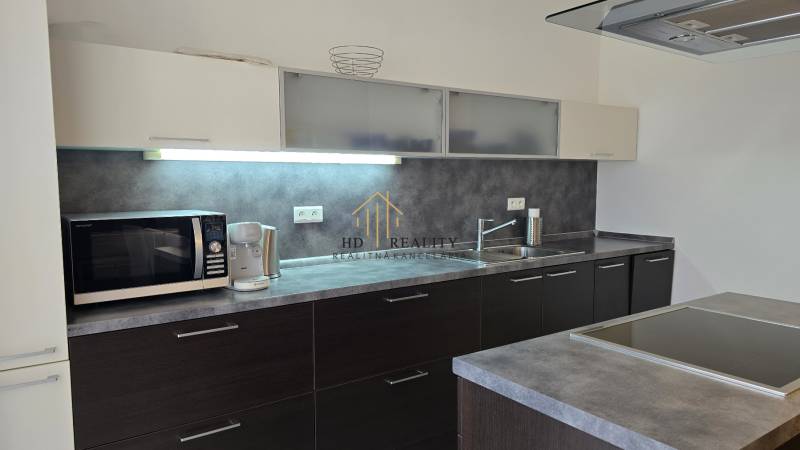 HD REALITY, Vám ponúka na Predaj 3-izbový Apartmán + Garážové státie - Kuchyňa v 3-izbovom byte, s tmavými skrinkami a spotrebičmi na pracovnej doske.