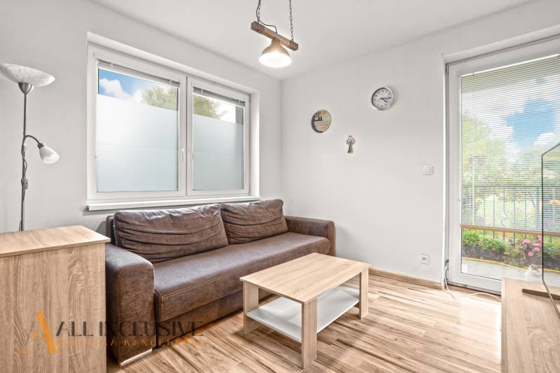 REZERVOVANÉ | NA PREDAJ 3-IZBOVÝ BYT S TERASOU, BLATNÁ NA OSTROVE - Obývačka v 3-izbovom byte s hnedou sedačkou a podlahou s dreveným dekorom.