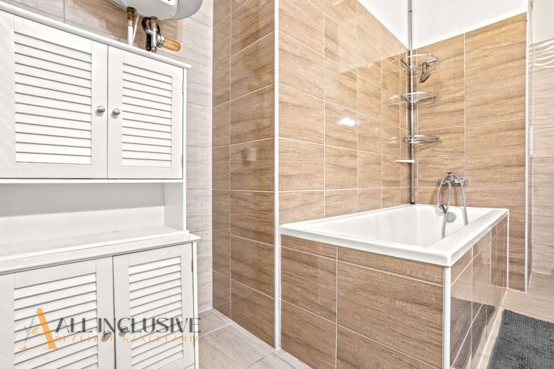 REZERVOVANÉ | NA PREDAJ 3-IZBOVÝ BYT S TERASOU, BLATNÁ NA OSTROVE - Kúpeľňa s vaňou, bielymi skrinkami a obkladom v 3-izbovom byte.