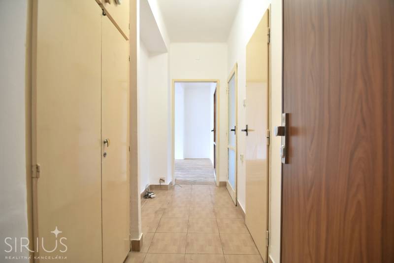 SEČOVSKÁ, 2-i tehlový byt, 56 m2, orientácia V a Z - OBKLOPENÝ ZELEŇOU - Chodba v 2-izbovom byte s dverami a podlahou s dreveným dekorom.