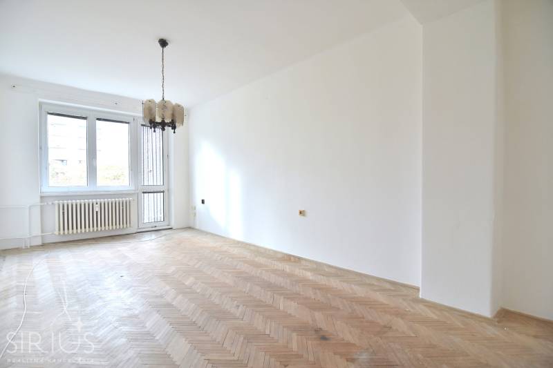 SEČOVSKÁ, 2-i tehlový byt, 56 m2, orientácia V a Z - OBKLOPENÝ ZELEŇOU - Svetlá miestnosť v 2-izbovom byte s podlahou s dreveným dekorom a závesným svietidlom.