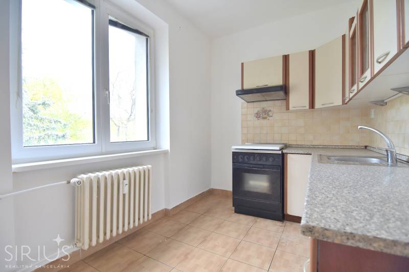 SEČOVSKÁ, 2-i tehlový byt, 56 m2, orientácia V a Z - OBKLOPENÝ ZELEŇOU - Kuchyňa v 2-izbovom byte s oknom, kuchynskou linkou a radiátorom.