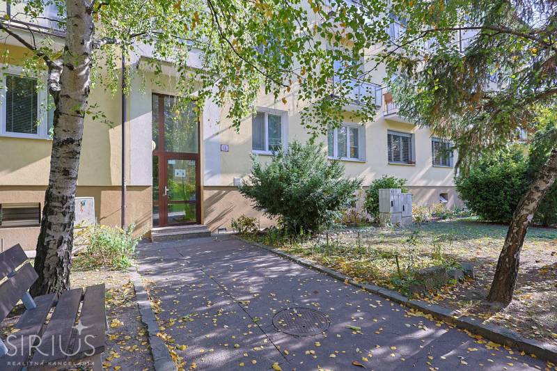 SEČOVSKÁ, 2-i tehlový byt, 56 m2, orientácia V a Z - OBKLOPENÝ ZELEŇOU - Vstup do bytovky na Sečovskej ulici v Bratislave - Ružinove, obklopený stromami a zeleňou.