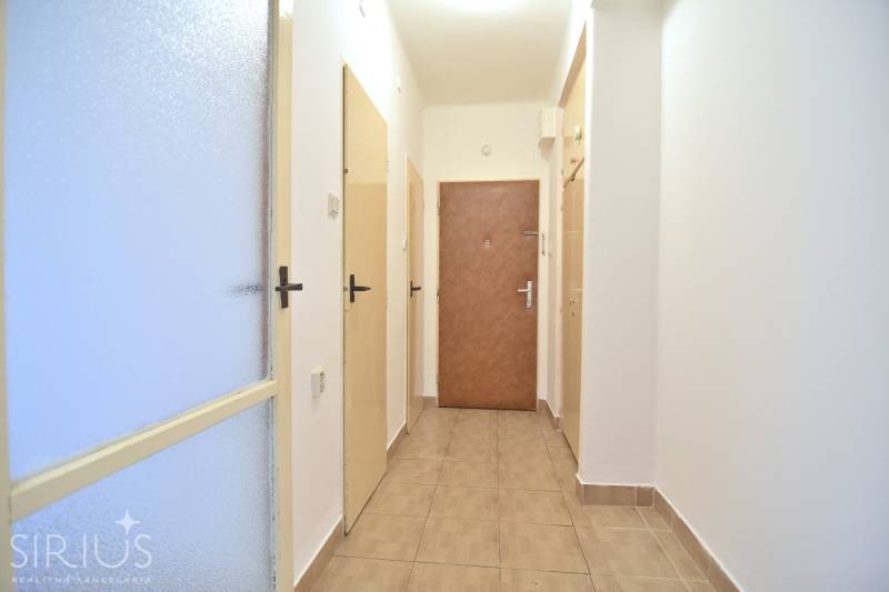 SEČOVSKÁ, 2-i tehlový byt, 56 m2, orientácia V a Z - OBKLOPENÝ ZELEŇOU - Vstupná chodba v 2-izbovom byte s dlažbou a viacerými dverami.