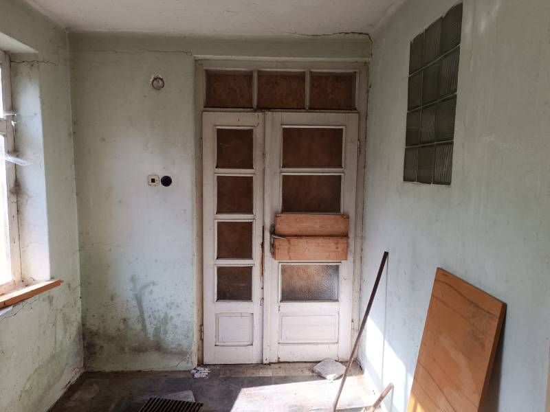 Hospodárska usadlosť  - Časť interiéru rodinného domu s presklenými dverami a stenou s malými oknami.