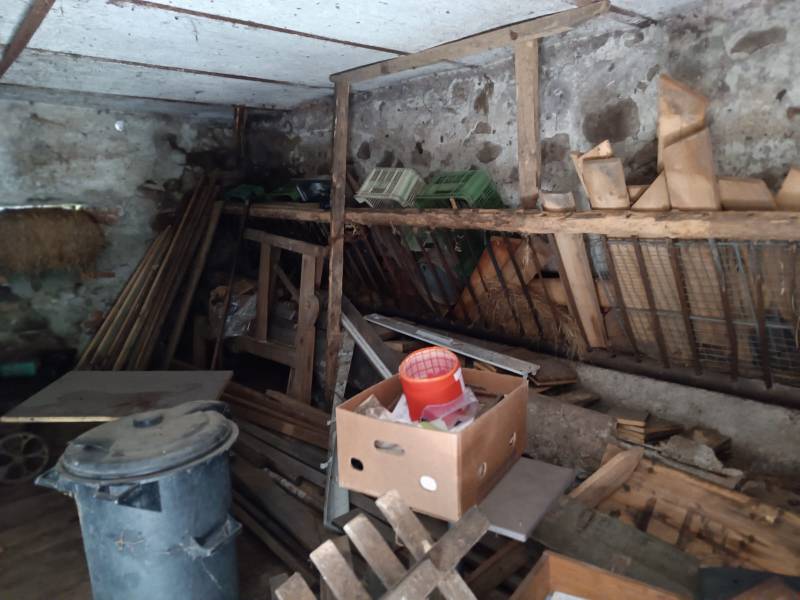 Hospodárska usadlosť  - Skladový priestor s rôznymi predmetmi v rodinnom dome, miestnosť s kameňmi a drevenými prvkami.