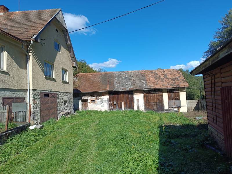 Hospodárska usadlosť  - Rodinný dom v Horných Hámroch so záhradou a drevenou prístavbou, pod modrou oblohou.