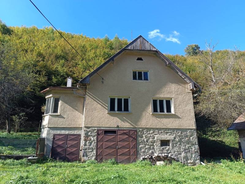 Hospodárska usadlosť  - Rodinný dom v Horných Hámroch v prírode s garážovými dverami a kamennou fasádou.