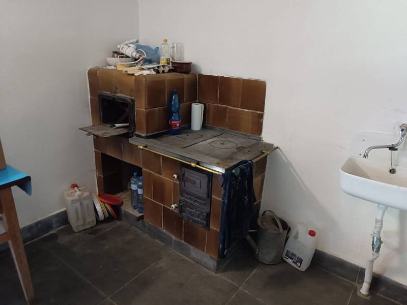 Hospodárska usadlosť  - Kachľová pec vedľa umývadla v interiéri rodinného domu.