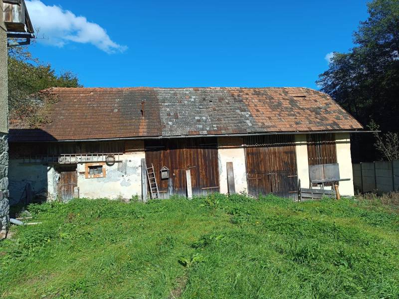 Hospodárska usadlosť  - Budova vedľa rodinného domu v Horných Hámroch s drevenými dverami a trávnatým okolím.