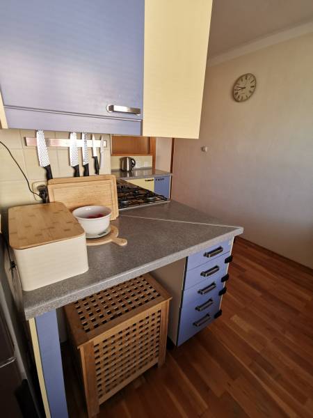 3 izbový byt Zlaté Moravce - Kuchyňa v 3-izbovom byte s modrými skrinkami a podlahou s dreveným dekorom.