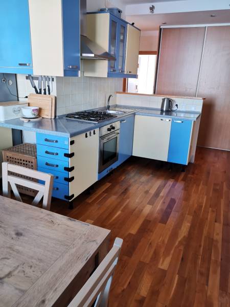 3 izbový byt Zlaté Moravce - Kuchyňa v 3-izbovom byte s farebnými skrinkami a podlahou s dreveným dekorom.