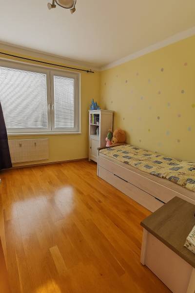 3 izbový byt Zlaté Moravce - Detská izba s posteľou, poličkou a podlahou s dreveným dekorom v 3-izbovom byte.