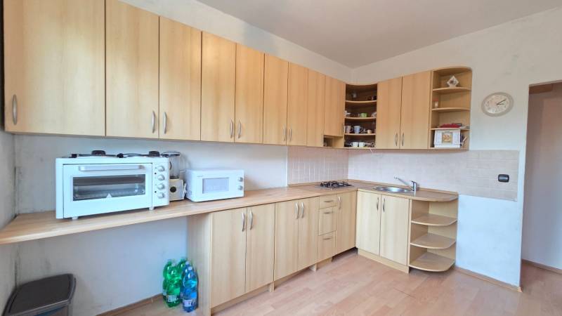 REZERVOVANÉ: NA PREDAJ -  1-izbový byt vo Veľkom Šariši - PREŠOV - Kuchyňa s kuchynskými skrinkami v 1-izbovom byte, vybavená spotrebičmi a podlahou s dreveným dekorom.