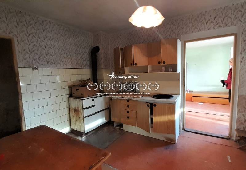 Rodinný dom v obci Dobrá Voda  - Kuchyňa rodinného domu s retro sporákom a svetlou tapetou na stenách.