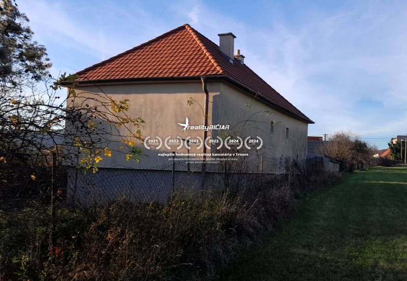 Rodinný dom v obci Dobrá Voda  - Rodinný dom v Dobrej Vode s červenou strechou a oplotením, obklopený zeleňou.