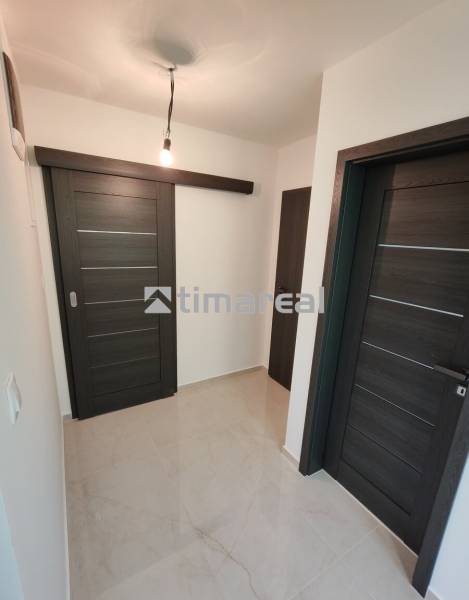 – Podpivničený RD po kompletnej rekonštrukcii - Chodba v 3-izbovom byte s tmavými posuvnými dverami a svetlou podlahou.