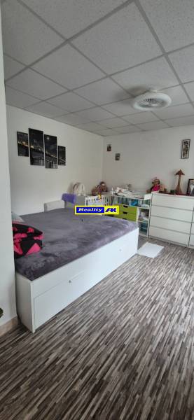 REZERVOVANÉ jednoizbový zrekonštruovaný byt v širšom centre mesta - Izba s podlahou s dreveným dekorom, posteľou a bielou komodou v 1-izbovom byte.