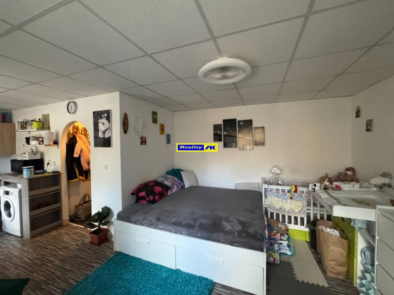 REZERVOVANÉ jednoizbový zrekonštruovaný byt v širšom centre mesta - Izba v 1-izbovom byte s posteľou a detskou postieľkou, podlaha s dreveným dekorom.