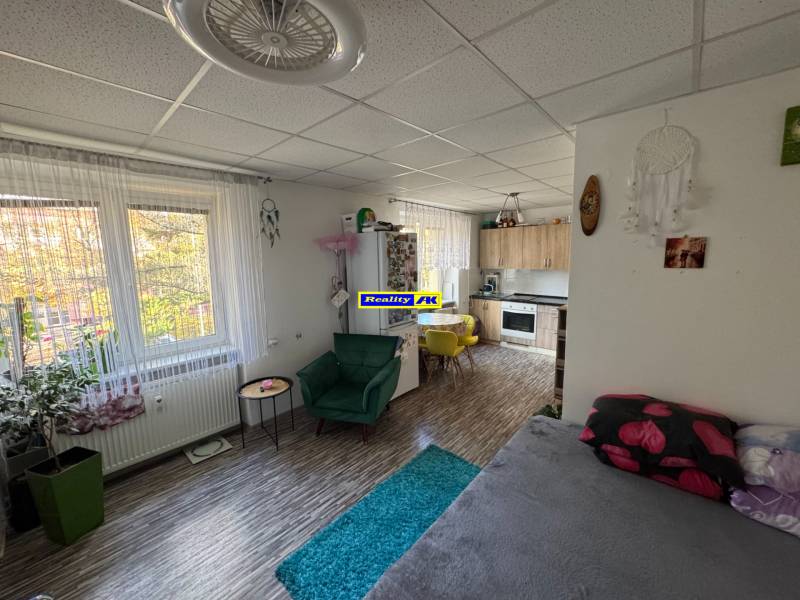 REZERVOVANÉ jednoizbový zrekonštruovaný byt v širšom centre mesta - Obývacia časť a kuchyňa v 1-izbovom byte s podlahou s dreveným dekorom.