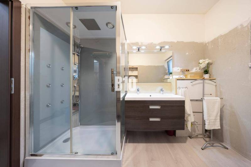 Tri Vody - 4-izbový rodinný dom s bazénom | Most pri Bratislave – Baza - Kúpeľňa v rodinnom dome s podlahou s dreveným dekorom, sprchovým kútom a zrkadlom.