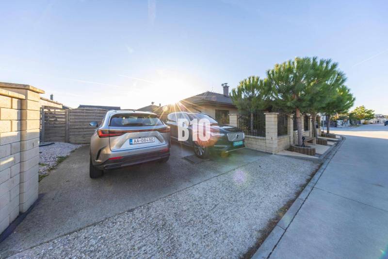 Tri Vody - 4-izbový rodinný dom s bazénom | Most pri Bratislave – Baza - Dvor rodinného domu v Mosti pri Bratislave s parkovacími miestami a zaparkovanými autami.