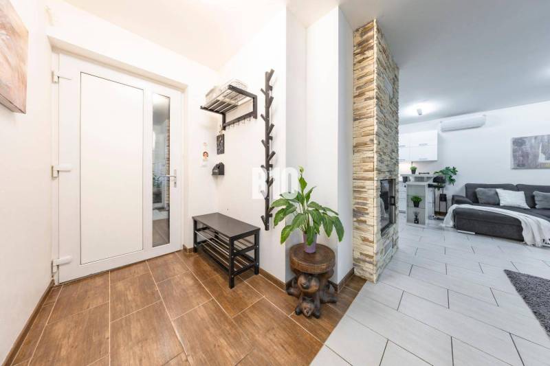 Tri Vody - 4-izbový rodinný dom s bazénom | Most pri Bratislave – Baza - Interiér rodinného domu s podlahou s dreveným dekorom, kamenným krbom a pohodlnou obývačkou.