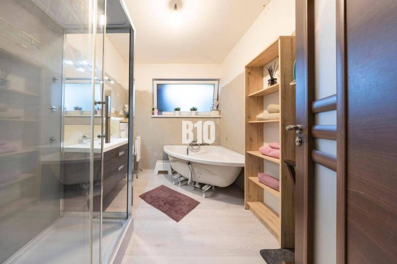 Tri Vody - 4-izbový rodinný dom s bazénom | Most pri Bratislave – Baza - Kúpeľňa v rodinnom dome s vaňou, sprchovým kútom a nábytkom s dreveným dekorom.