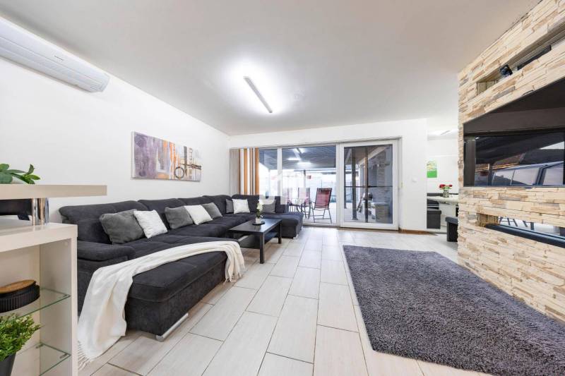 Tri Vody - 4-izbový rodinný dom s bazénom | Most pri Bratislave – Baza - Obývacia izba rodinného domu s pohovkou, krbom a posuvnými dverami na terasu.