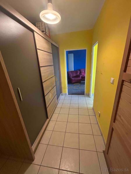 Veľký 2-izb. byt na ul. Vranovská, Petržalka, lodžia, 4.p./7 - Chodba garsónky s dlažbou, skriňami a žltými stenami, vedie do miestnosti s modrými stenami.