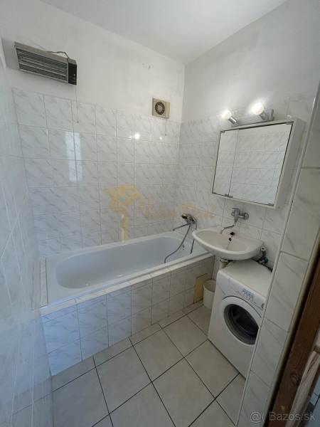 Veľký 2-izb. byt na ul. Vranovská, Petržalka, lodžia, 4.p./7 - Kúpeľňa v garsónke s vaňou, umývadlom, práčkou a dlažbou s bielymi obkladmi.