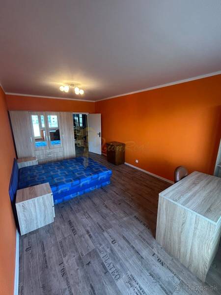 Veľký 2-izb. byt na ul. Vranovská, Petržalka, lodžia, 4.p./7 - Oranžová garsónka s posteľou, skriňou a podlahou s dreveným dekorom.