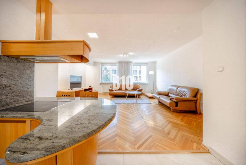 POD HRADOM - ZÁMOCKÁ - 3 IZBOVÝ BYT NA BÝVANIE AJ INVESTÍCIU - Obývacia izba v 3-izbovom byte s podlahou s dreveným dekorom a koženým nábytkom.